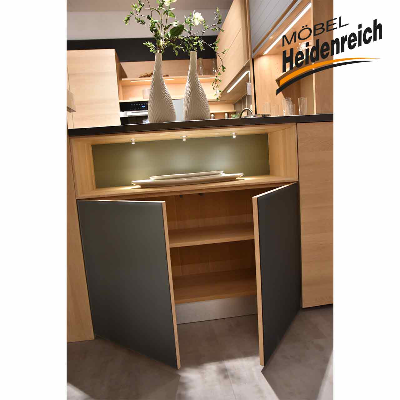 Geöffneter Unterschrank, man sieht zwei Fächer. Über dem Unterschrank ist ein offenes Fach mit Beleuchtung.