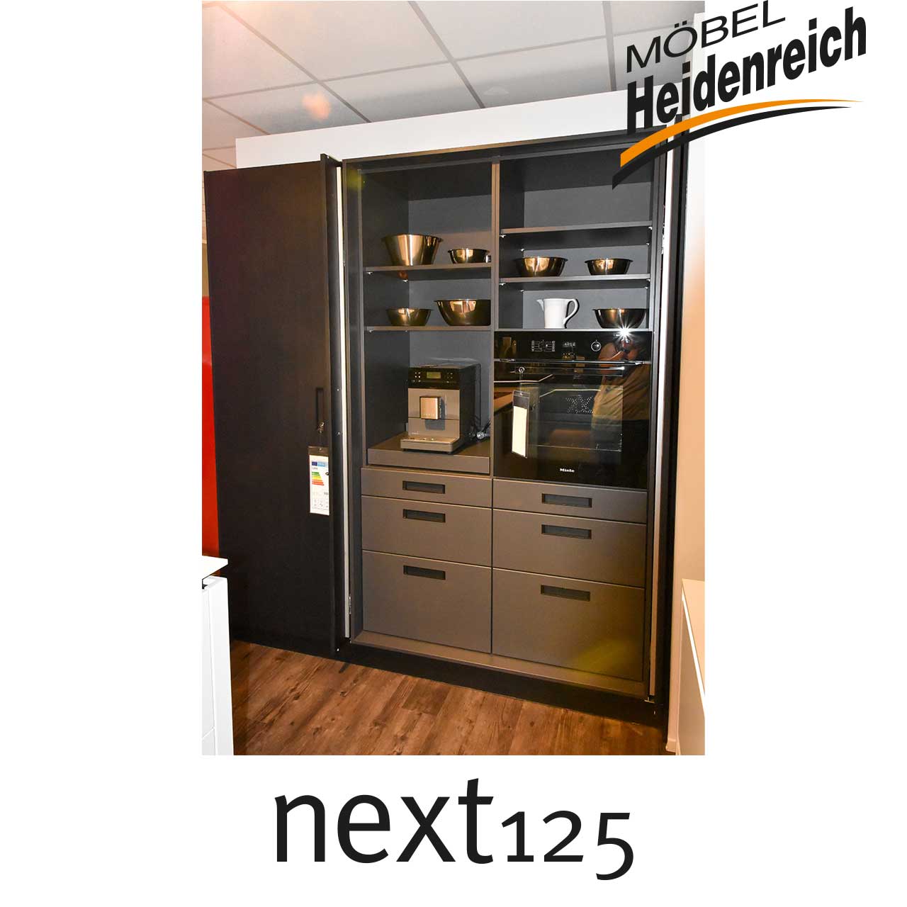 Dunkle Küchenzeile mit Regalen und Schubladen sowie Platz für Kafeemaschine.