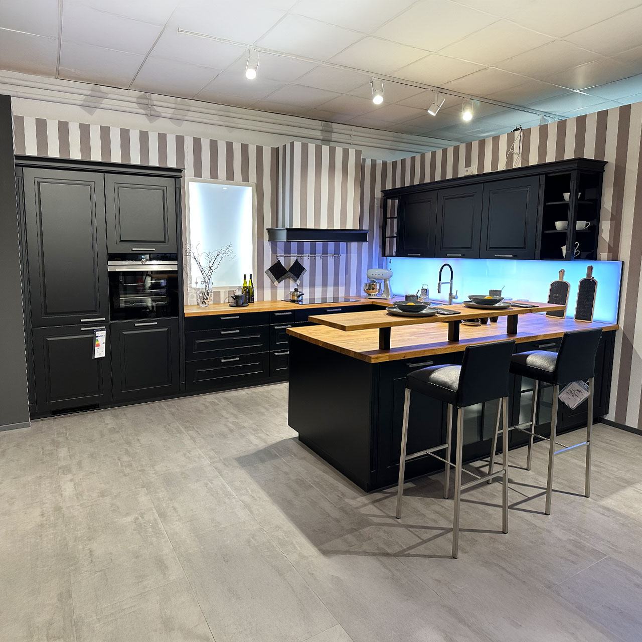 Schwarze Küche mit Holztheke und Holzarbeitsplatte im modernen Landhaus-Stil (Kassettentüren).