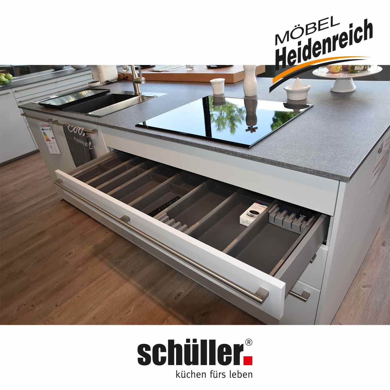 Die Schublade unter dem Kochfeld ist geöffnet. Hier ist eine große Besteckeinlage sichtbar.