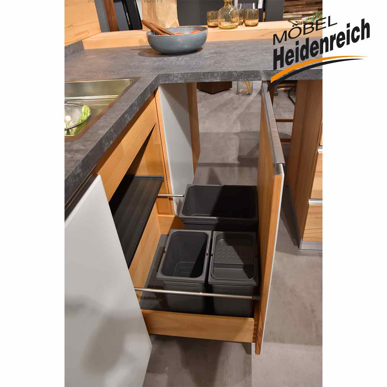 Schublade unter Spüle ist aufgezogen und gibt den Blick auf ein dreiteiliges Mülleimer-Set frei.
