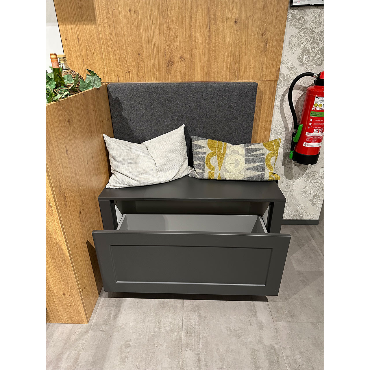 Kleine Bank mit zwei Kissen und ausgezogenem Fach darunter.