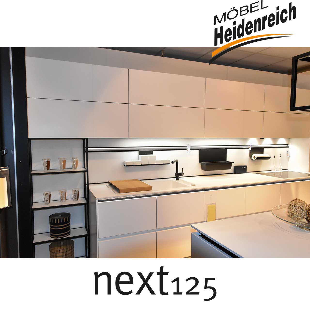 next125 Küche - Detail Küchenzeile Küchenzeile mit acht Oberschränken und darunter die weiße Spüle mit schwarzer Armatur.