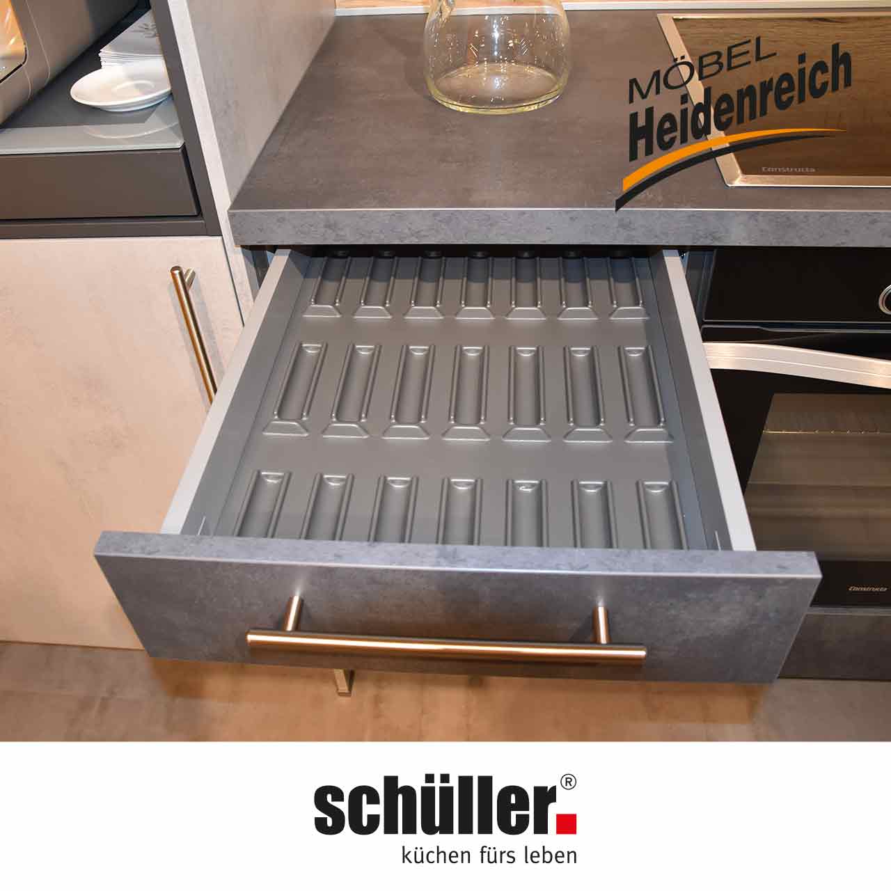 Geöffnete Schublade links neben Kochfeld mit Besteckeinsatz.