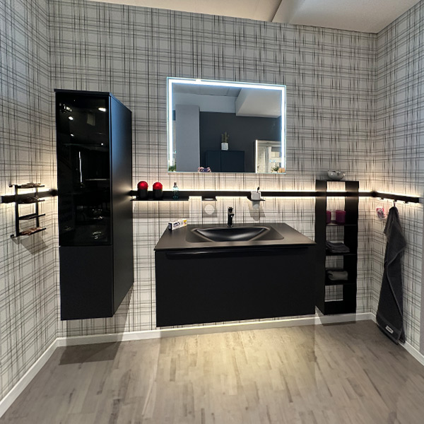 Schwarzes Badmöbel mit umlaufender beleuchteter Reling, an der von links nach recht hängen: Brillenregal, Hängevitrine, Ablagefach, Becherhalter, Hängeregal, Haken. 