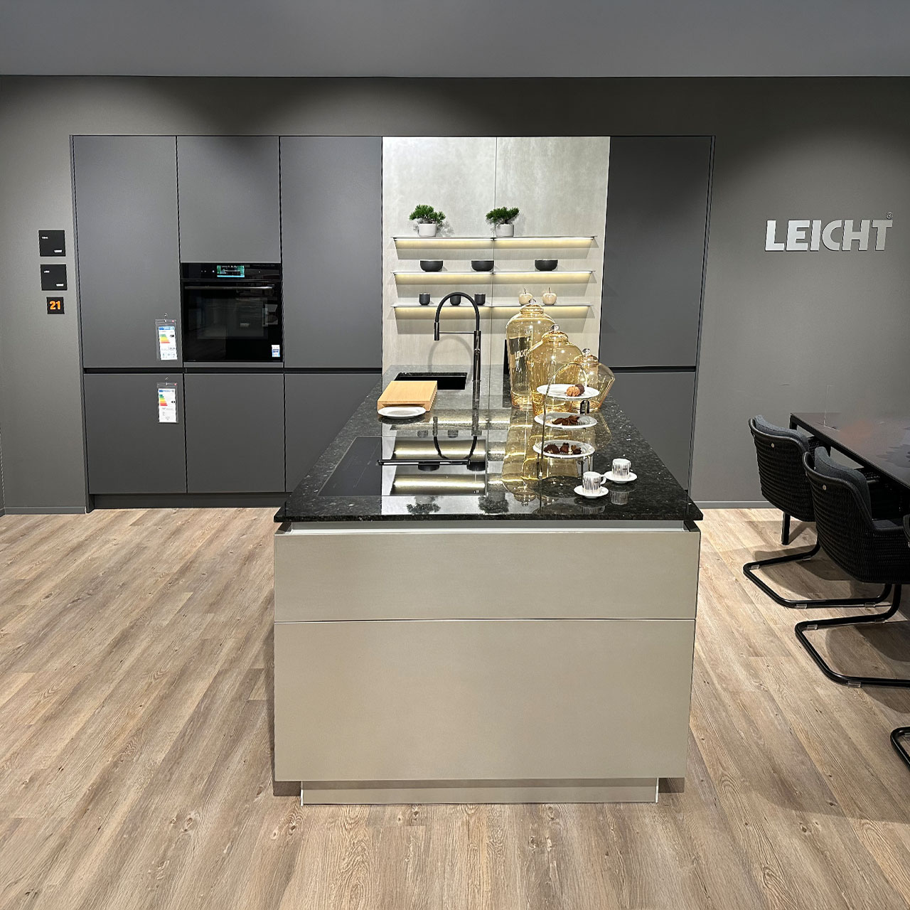 Moderne LEICHT Designküche in Grau mit Kücheninsel, schwarzer Naturstein-Arbeitsplatte und integrierten Einbaugeräten.