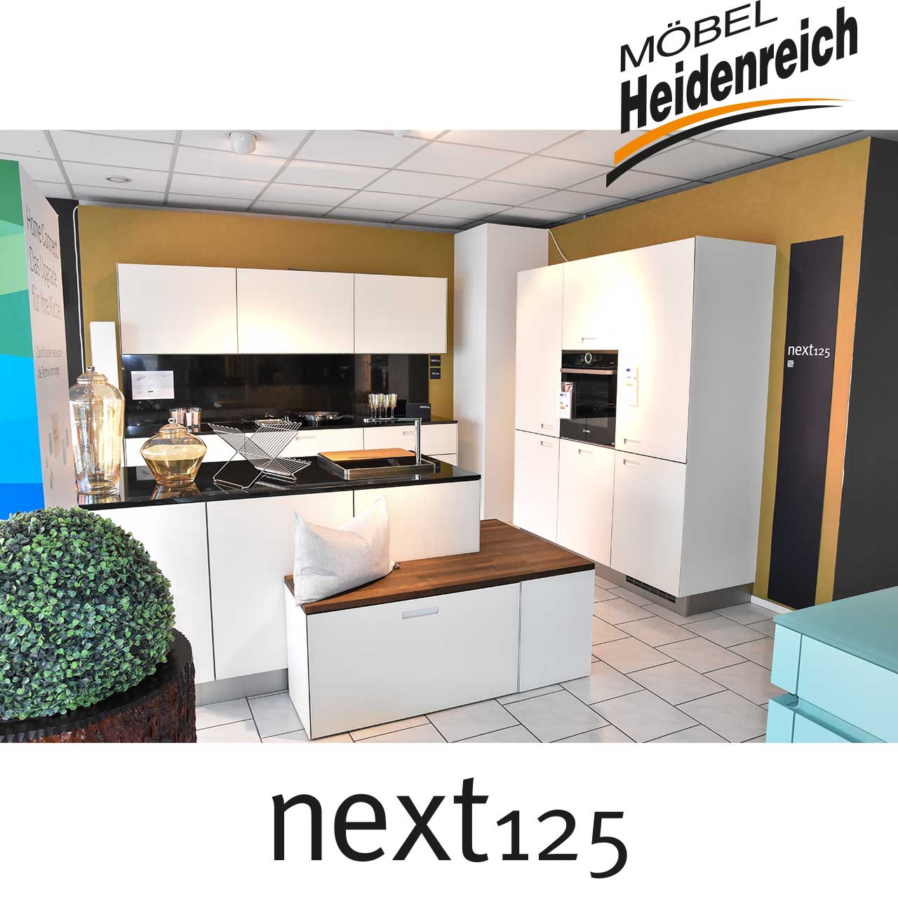 Weiße Einbauküche mit schwarzer Arbeitsfläche und Sitzbereich mit Holzabdeckung.