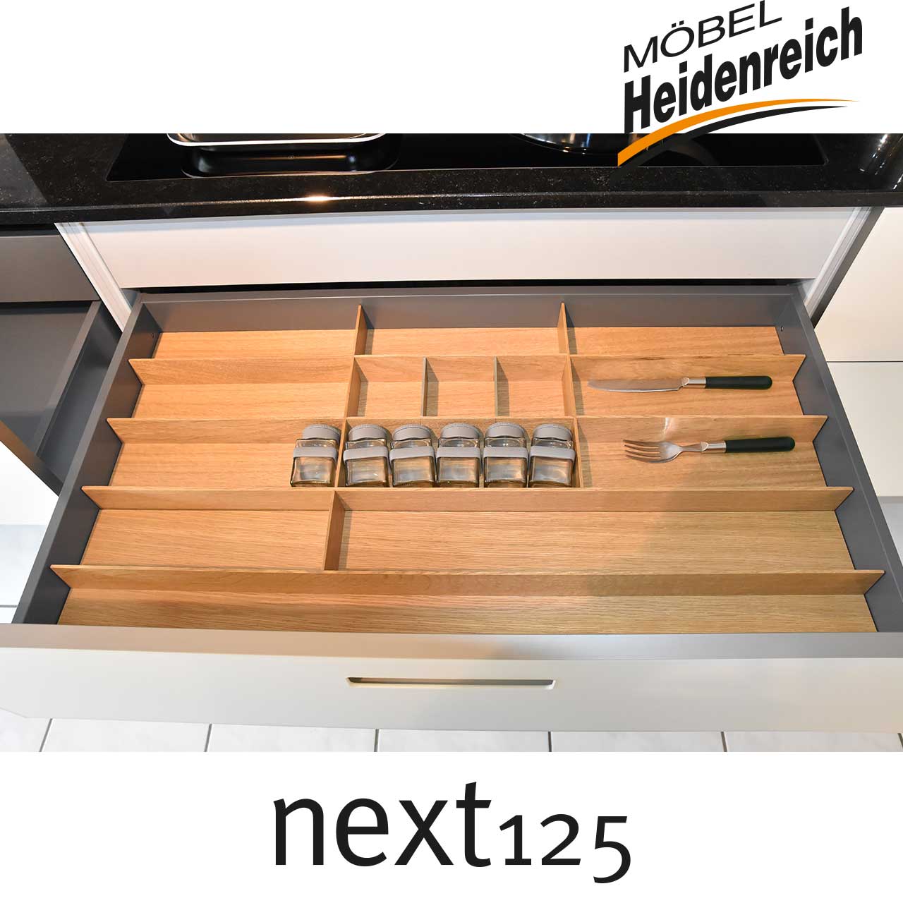 Geöffnete Schublade mit Besteckeinsatz aus Holz.