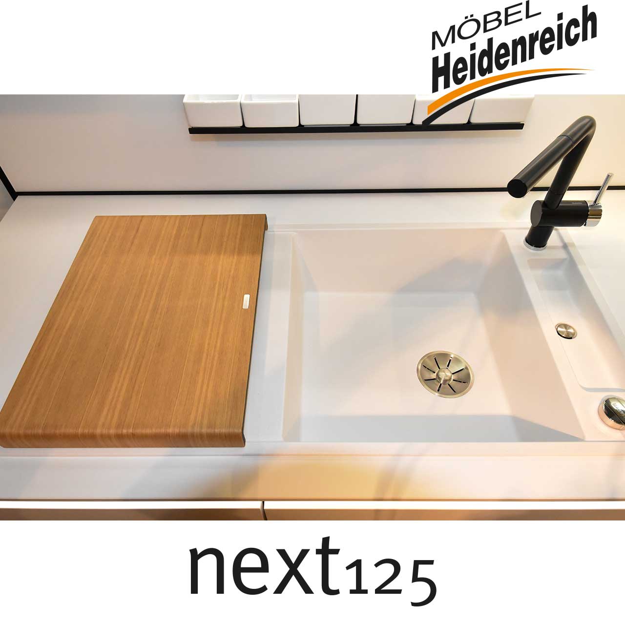 next125 Küche - Detail Spüle Weiße eckige Spüle mit schwarzer Armatur.