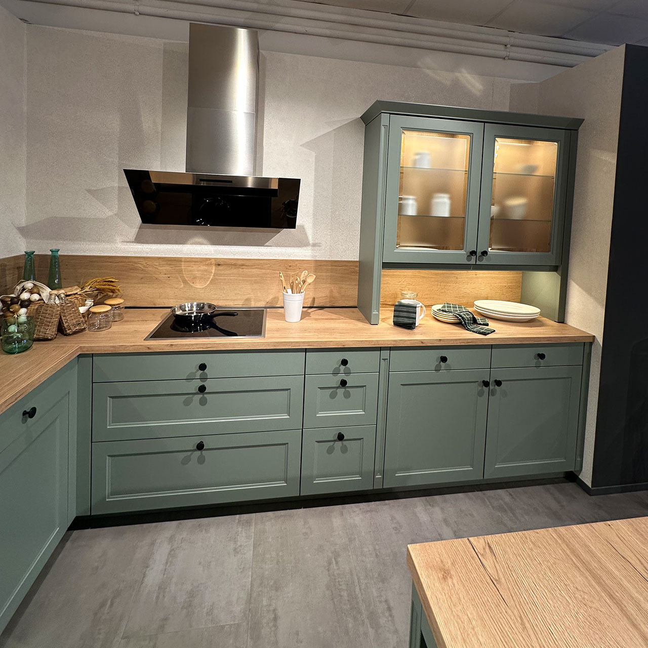 Hier findet sich links das Kochfeld mit Abzug. Rechts Oberschrank mit Glasfront, darunter Türen und Schubladen 