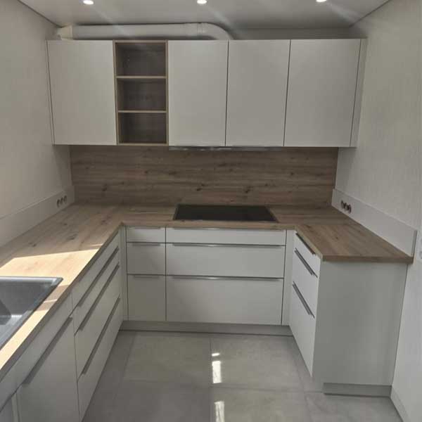 Küche Familie Volz Weiße Küche mit Arbeitsplatte in heller Holzoptik sowie Rückwand in gleicher Optik.