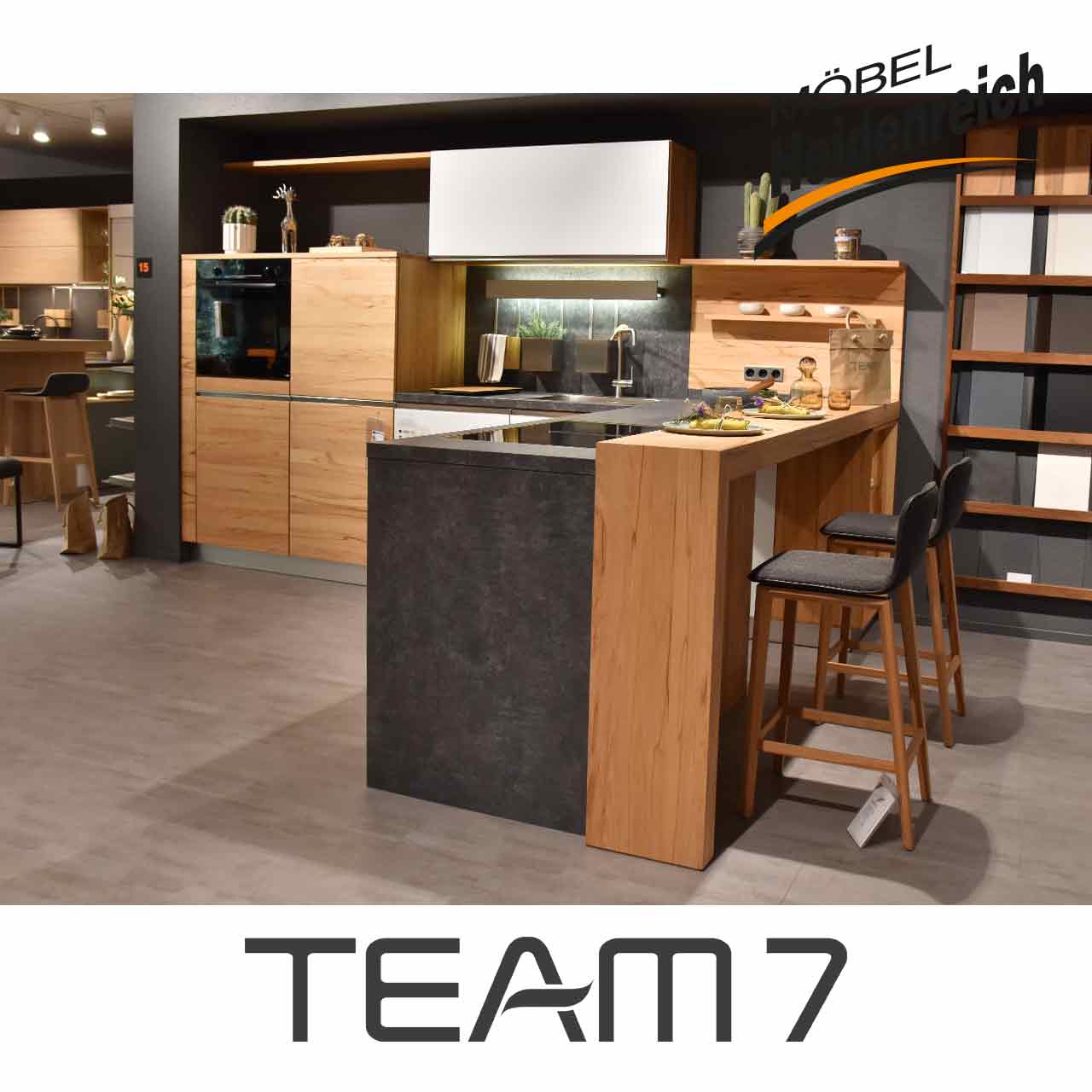 Team7 Küche - Seitenansicht Blick auf die Kochinsel mit zwei Barstühlen daneben.