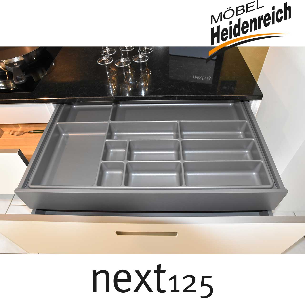 Geöffnete Schublade mit Besteckeinsatz aus grauem Plastik.